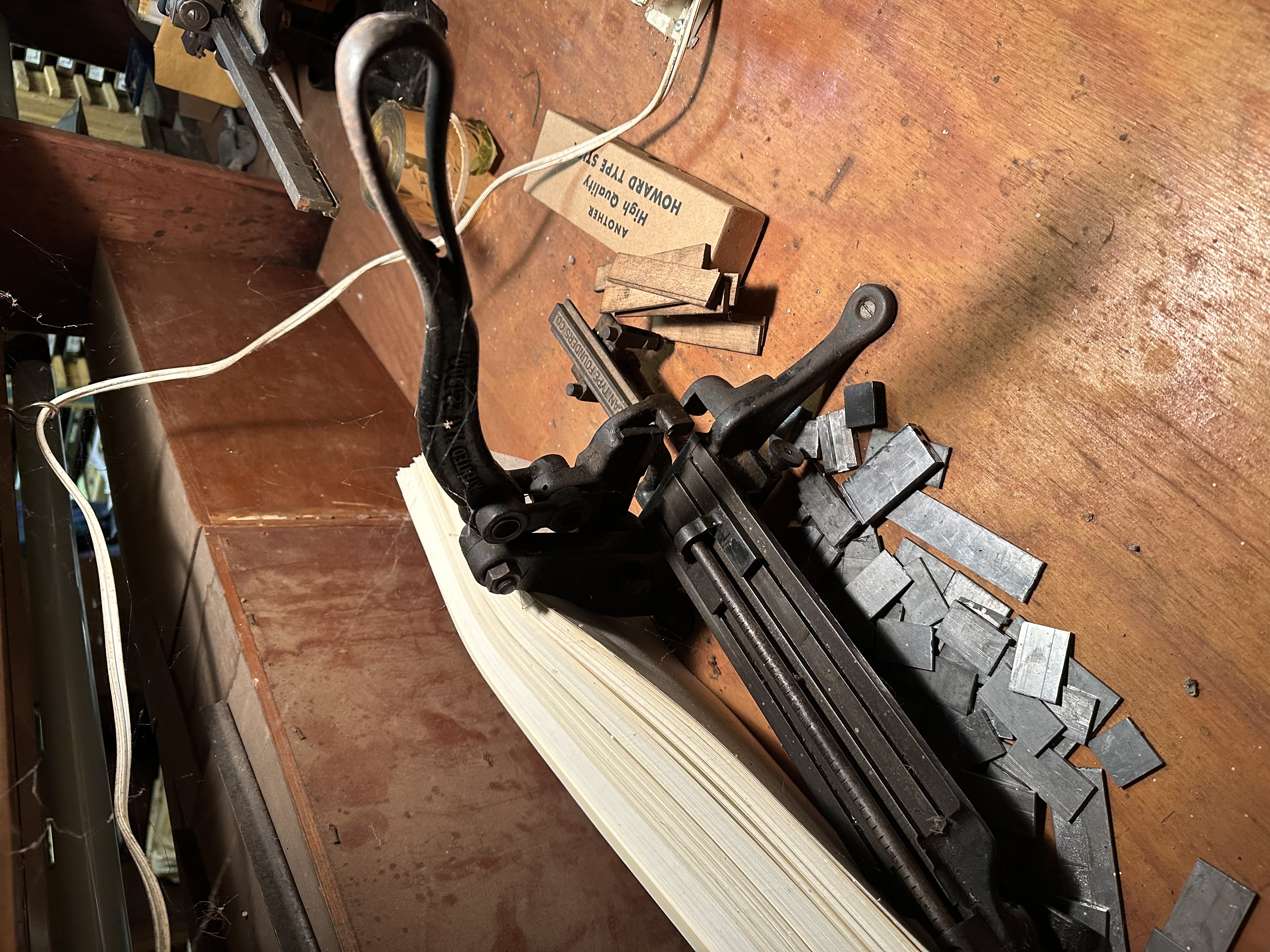 A paper cutter and metal type on a wooden bench